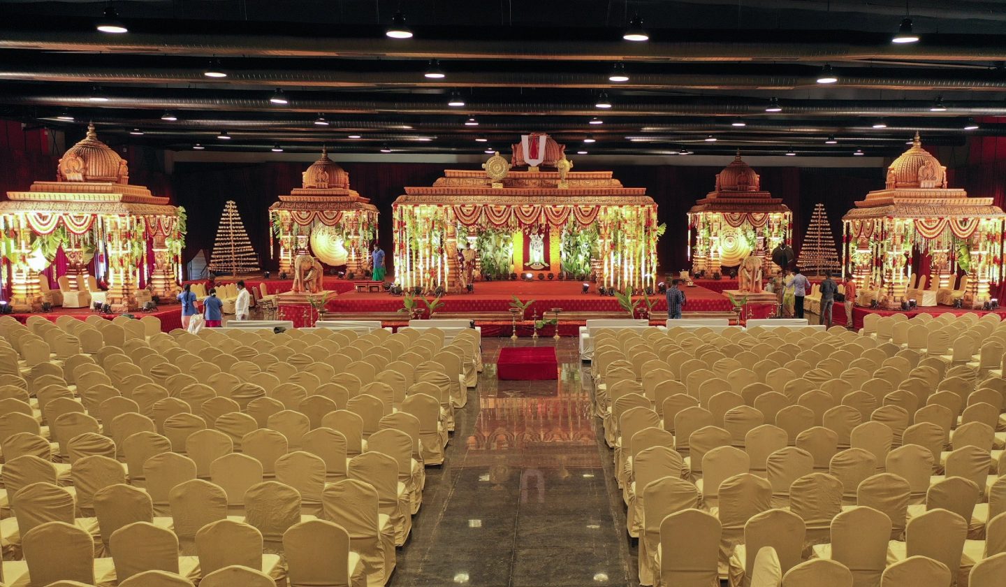 Emerald hall dressed for a wedding with a monumental gilded mandapam, gold chair covers and a full house